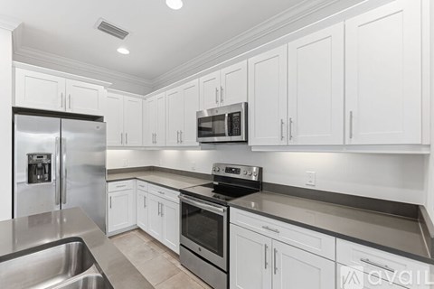 A modern kitchen with white cabinets and stainless steel appliances.