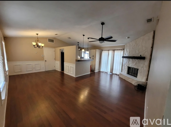 A spacious room with wood flooring and a ceiling fan.