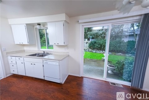 A kitchen with white cabinets and a wooden floor.
