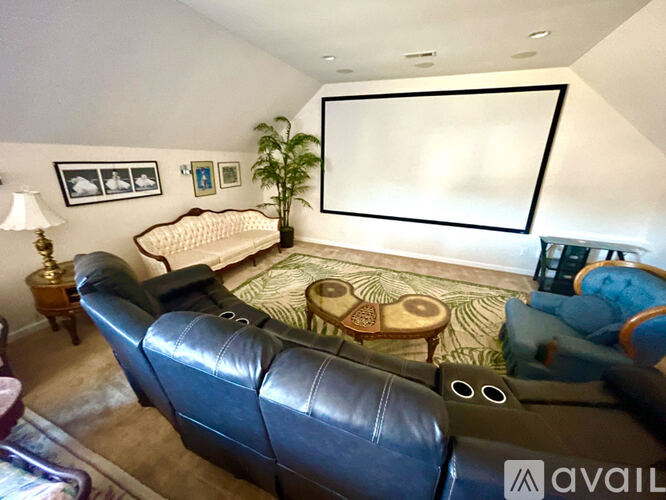 A living room with a black leather couch and a white sofa.