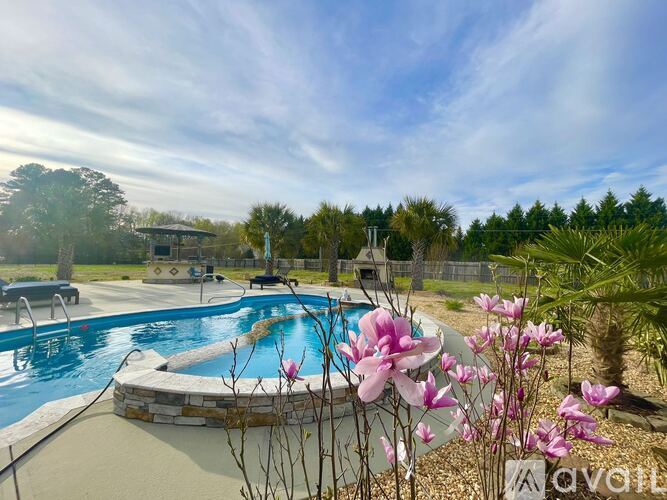 A pool surrounded by a stone wall with pink flowers in the foreground.
