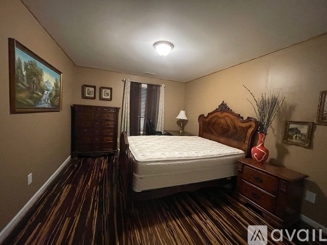 A bedroom with a bed, dresser, and painting on the wall.