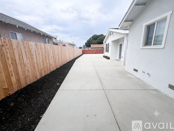 A long concrete walkway separates two rows of houses.