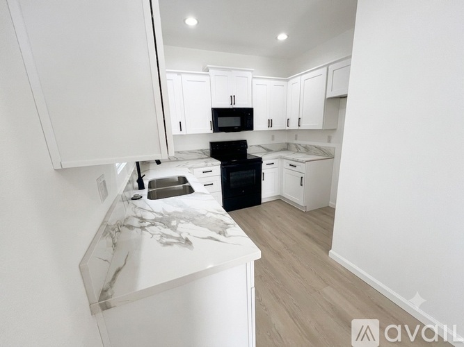 A kitchen with white cabinets and a black stove top oven.