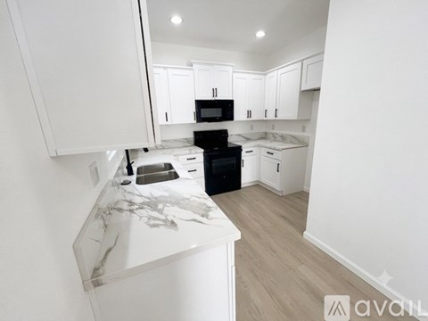A kitchen with white cabinets and a black stove top oven.