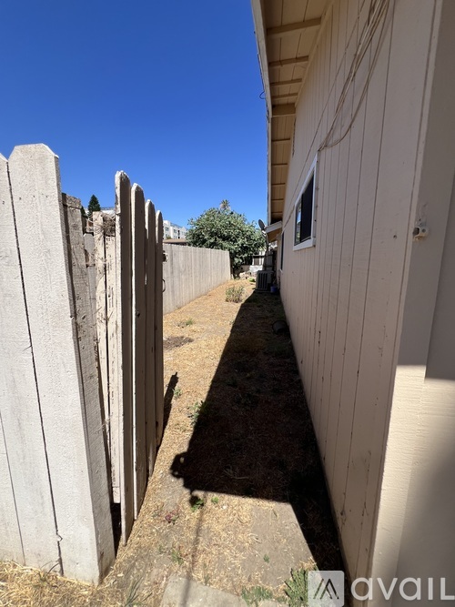 A white fence runs along the side of a building.