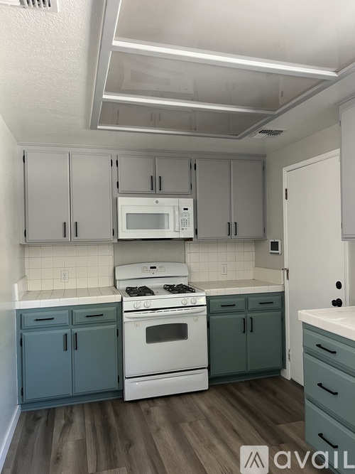 A kitchen with white cabinets and a white stove top oven.
