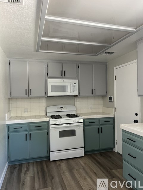 A kitchen with white cabinets and a white stove top oven.