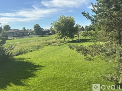 A grassy field with trees and a house in the background.