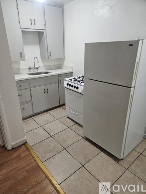 A kitchen with a white refrigerator, stove, and sink.
