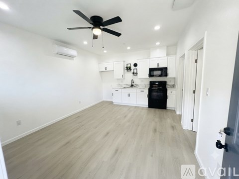 A spacious kitchen with a black oven and white cabinets.
