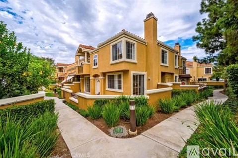 A yellow house with a white fence and a brown post in front of it.