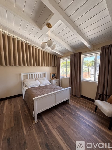 A bedroom with a bed, a chair, and a window.