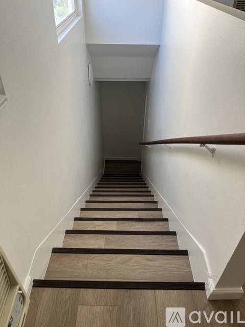 A set of stairs with wooden treads and white walls.