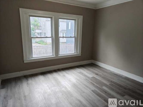 A room with a large window and wooden flooring.
