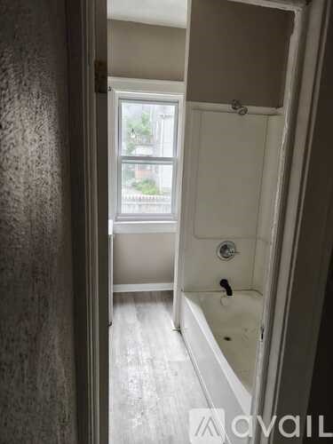 A bathroom with a tub and a window.