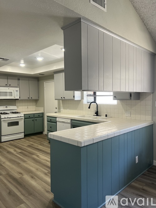 A kitchen with a white counter top and green cabinets.
