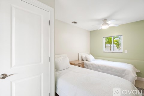 A bedroom with two beds and a window showing greenery outside.
