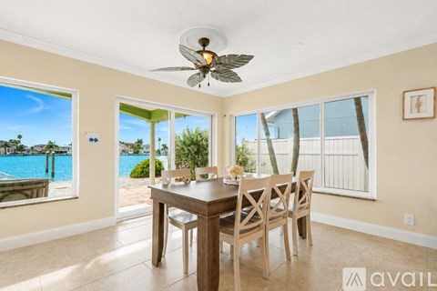 A dining room with a table and chairs and a view of the pool.