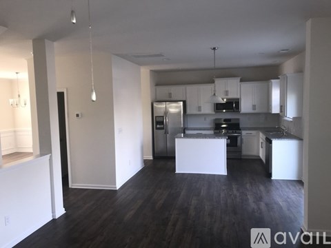 A kitchen with white cabinets and a dark floor.