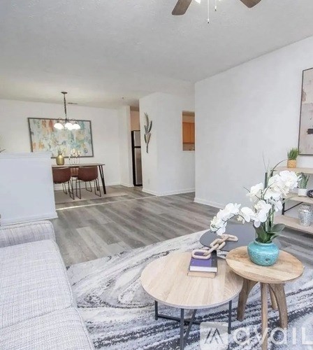 A living room with a white couch, a wooden coffee table, and a rug with a grey and white pattern.