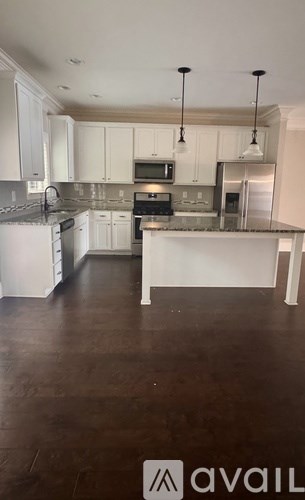 A kitchen with white cabinets and a dark floor.