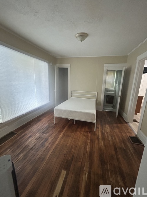 A bedroom with a bed and wooden floors.