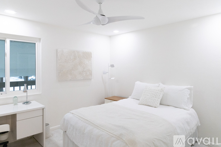 A bedroom with a white bed and a ceiling fan.