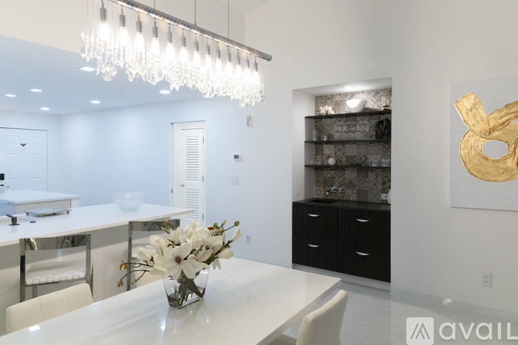 A modern dining room with a white table and a chandelier.