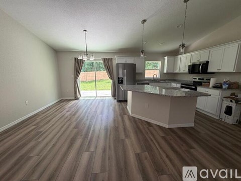 A kitchen with a wooden floor and white cabinets is available for rent.