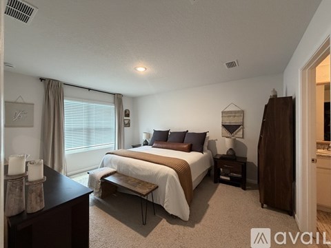 A bedroom with a large bed and a window with curtains.