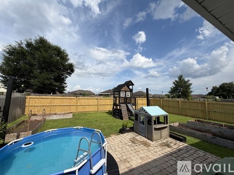 A backyard with a pool and a playhouse.
