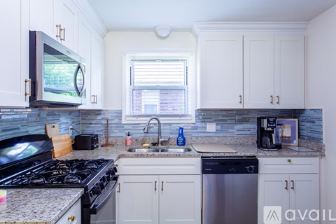 A kitchen with a black stove top oven and white cabinets.