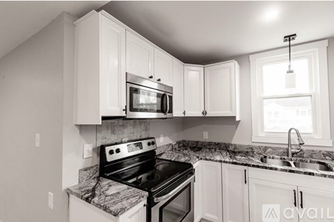 A kitchen with white cabinets and a black stove top oven.