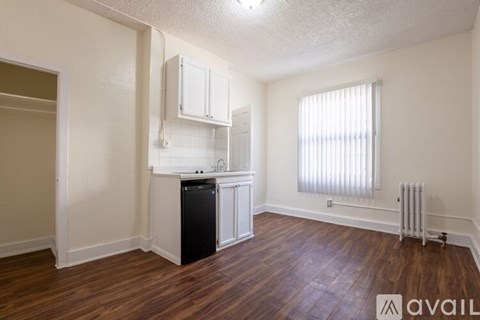 A room with wooden floors and a black and white fridge.
