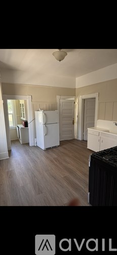A kitchen with a white refrigerator and wooden floors.
