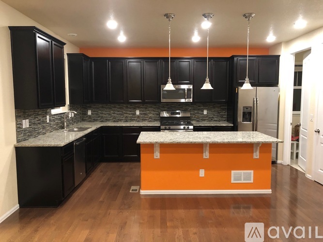 A kitchen with black cabinets and a granite countertop.