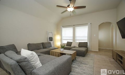 A living room with a grey couch and a ceiling fan.