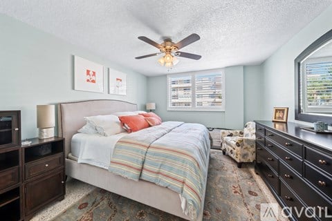 A bedroom with a bed, dresser, and ceiling fan.