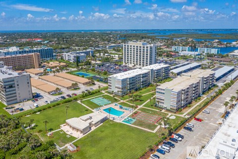 A large complex with a pool and a parking lot.