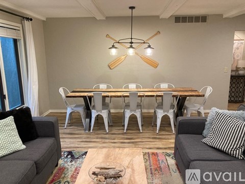 A living room with a grey couch, a wooden table with chairs, and a rug on the floor.