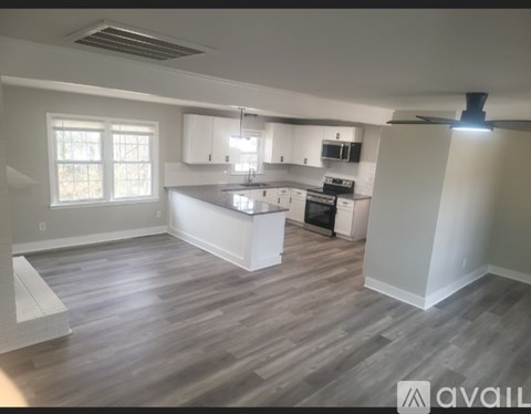 A kitchen with white cabinets and a wooden floor.