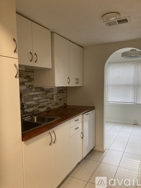 A kitchen with white cabinets and a wooden countertop.