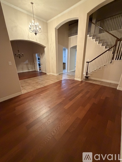 A spacious room with wooden flooring and a staircase.