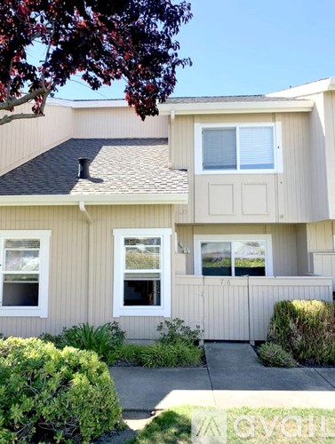 A house with a beige exterior and a black roof.