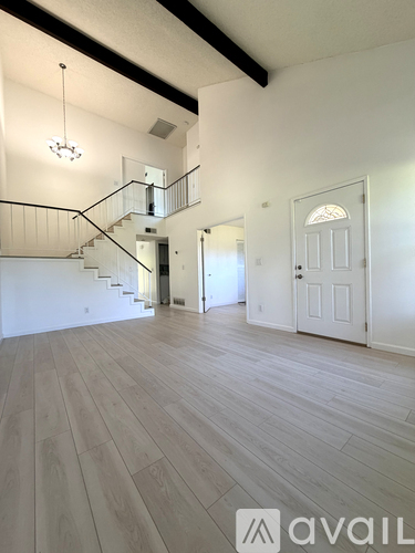 A spacious room with a staircase and a chandelier.