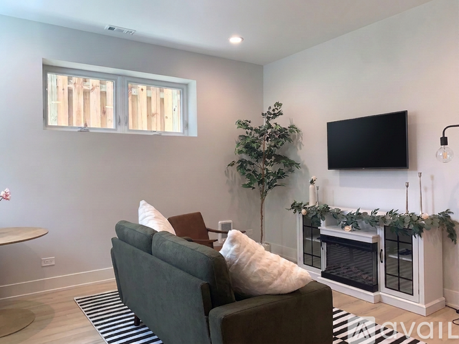 A living room with a grey couch, a white wall, and a black TV mounted on the wall.