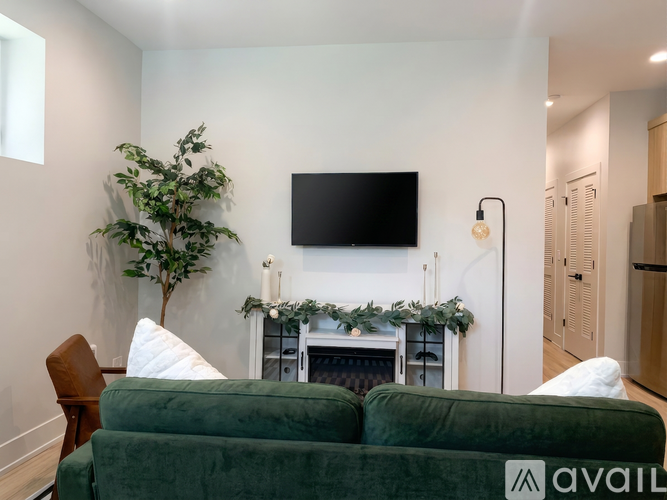 A living room with a green couch and a flat screen TV mounted on the wall.