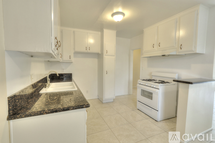 A kitchen with white cabinets and a black countertop.