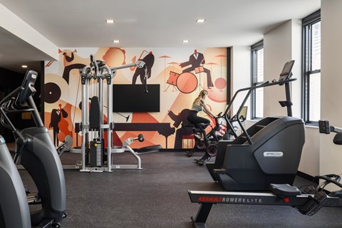 A gym with a rowing machine and a television.